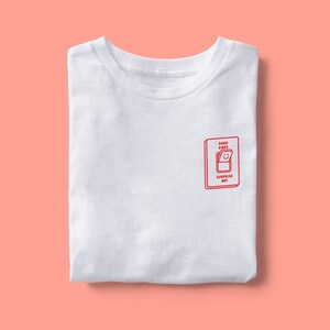 Op de afbeelding: Wit T-shirt met een rode afbeelding van een lichtschakelaar met de tekst "Good Vibes Surprise Me!"