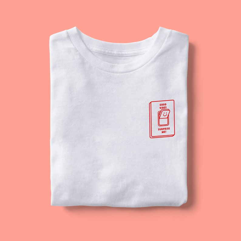 Op de afbeelding: Wit T-shirt met een rode afbeelding van een lichtschakelaar met de tekst "Good Vibes Surprise Me!"