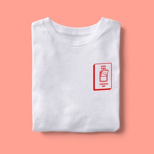 Op de afbeelding: Wit T-shirt met een rode afbeelding van een gesloten deur met de tekst "GOOD VIBES" en "SURPRISE ME!" erop.