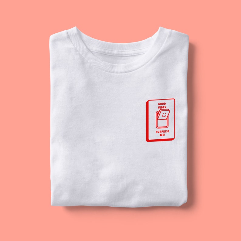 Op de afbeelding: Wit T-shirt met een rode afbeelding van een gesloten deur met de tekst "GOOD VIBES" en "SURPRISE ME!" erop.