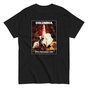 May include: Black t-shirt with a graphic of the Space Shuttle Columbia launching. The graphic is in a vintage style with a red, orange, and yellow color scheme. The text "COLUMBIA" is at the top of the graphic, and the text "STS 2, November 1981" is at the bottom.