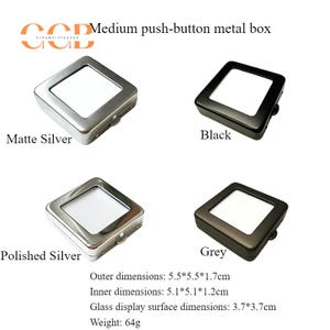 K&ouml;nnte beinhalten: Vier mittelgro&szlig;e Metallboxen mit Druckknopf in mattem Silber, Schwarz, poliertem Silber und Grau. Jede Box hat eine transparente Glas-Displayoberfl&auml;che. Au&szlig;enma&szlig;e: 5,5 x 5,5 x 1,7 cm. Gewicht: 64 g.