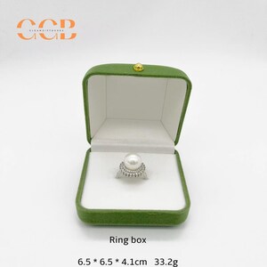 May include: Open green velvet ring box with a white interior, holding a pearl ring. The ring box is labeled "Ring box" and measures 6.5 x 6.5 x 4.1 cm and weighs 33.2g.