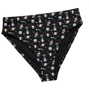 Könnte beinhalten: Schwarzer Slip mit einem Weltraum-Muster. Das Design umfasst rosa und blaue Planeten, Raketen, UFOs, Aliens, Sterne und Monde. Der Slip hat einen hohen Bund.