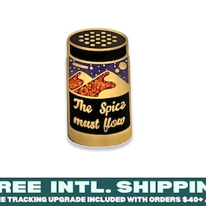 Può includere: Spilla in smalto color oro a forma di barattolo di spezie con coperchio nero e design viola e arancione. Il testo "The Spice must flow" è stampato sul barattolo.