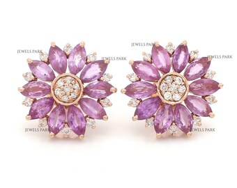 May include: A pair of floral stud earrings. Each earring features a central cluster of small white stones surrounded by pink marquise-cut stones, set in a rose gold metal.