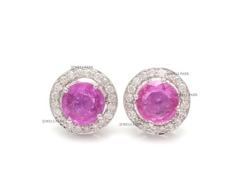 May include: A pair of pink sapphire earrings with a halo of diamonds set in white gold.
