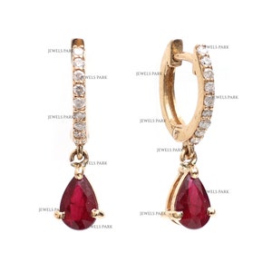 May include: A pair of gold hoop earrings with a teardrop-shaped ruby dangling from each hoop. The hoops are set with small diamonds.