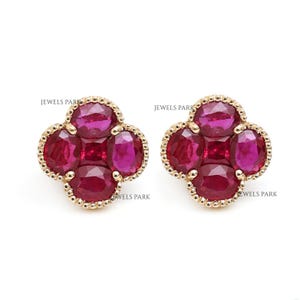 Puede incluir: Un par de pendientes de oro con un grupo de cinco piedras preciosas de rubí rojo en forma de trébol.