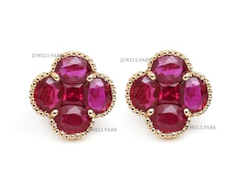 May include: A pair of gold earrings featuring a cluster of five red ruby gemstones in a clover shape.