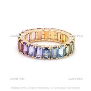 May include: A gold band ring with a rainbow of rectangular gemstones. The gemstones are set in a continuous line around the band.
