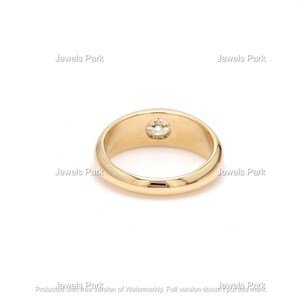 May include: A gold band ring with a single round diamond set in the center.