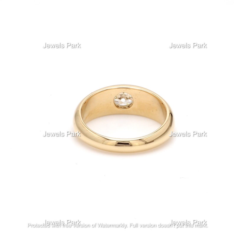 May include: A gold band ring with a single round diamond set in the center.