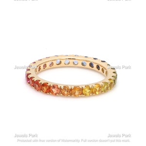 May include: A gold band ring with a rainbow of sapphires set in a continuous line around the band.