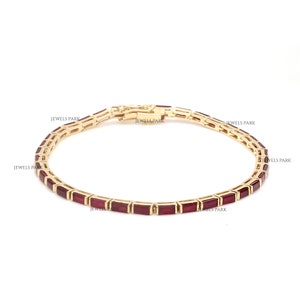 Pode incluir: Uma pulseira de ouro com uma fileira de pedras preciosas retangulares vermelhas. A pulseira é feita de ouro 14 quilates e tem um fecho seguro.