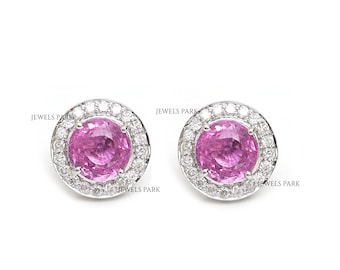 May include: A pair of pink sapphire earrings with a halo of diamonds set in white gold.