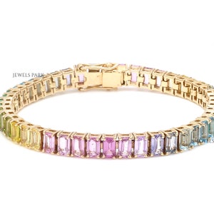 May include: A gold bracelet with a rainbow of rectangular gemstones. The bracelet is made of a delicate chain and has a clasp closure.