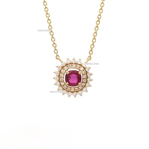 May include: A gold necklace featuring a pendant with a large, round, ruby-colored gemstone at the center, surrounded by a halo of smaller, clear gemstones. The necklace chain is also gold. The text "JEWELS PARK" is visible.