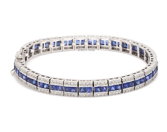 May include: A silver bracelet with a row of blue sapphire and diamond stones. The bracelet has a square-shaped design and is set in a white metal.