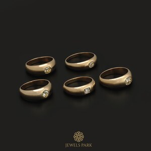 May include: Five gold rings with different shaped gemstones. The rings are on a black background. JEWELS PARK is written in gold at the bottom of the image.