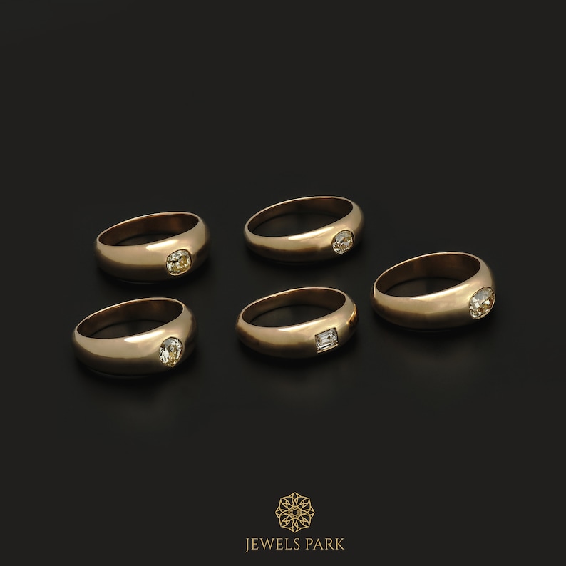May include: Five gold rings with different shaped gemstones. The rings are on a black background. JEWELS PARK is written in gold at the bottom of the image.