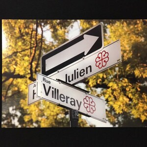 May include: A street sign with a white arrow pointing to the right. The sign reads "Rue Julien" and "Villeray" with a red clover symbol on each sign.