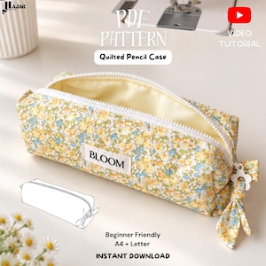 以下が含まれることがあります： 黄色、青、緑の花柄のキルティングペンケース。白いファスナーと「BLOOM」と書かれた白い布製ラベルが付いています。お揃いの布製ファスナー引き手と、ペンケースのデザインを描いた線画イラストが含まれています。