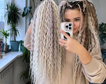 60 DE long wavy hair extensions in shades of blonde and light taupe in loose, textured waves with several thin braids interwoven throughout