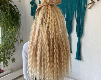 Long and have a natural hair extensions with ombre effect, transitioning from light brown to blonde
