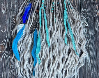 A set of gray and white wavy synthetic dreadlocks with blue and teal accents decorated with blue feathers, turquoise beads and ribbon