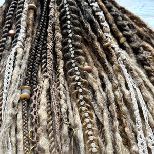 May include: A set of brown, blonde, and white synthetic dreadlocks with beads and crocheted lace accents.