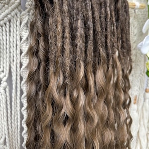 Puede incluir: Primer plano de rastas marrones y rubias con textura ondulada. Las rastas son una mezcla de marrón oscuro en las raíces, que transicionan a rubio más claro en los extremos. El cabello está peinado de forma natural y fluida.