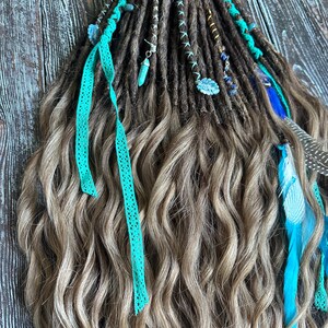 May include: A set of brown and blonde synthetic dreadlocks with turquoise and blue accents. The dreadlocks are decorated with turquoise beads, feathers, and turquoise lace ribbons.
