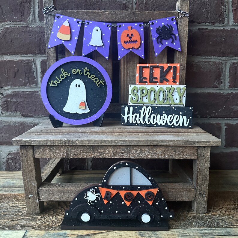 May include: A wooden Halloween decoration set with a purple and black "trick or treat" sign with a ghost, a stack of wooden blocks that read "EEK! SPOOKY HALLOWEEN", and a black and white car with a spider and "BOO" on the back.