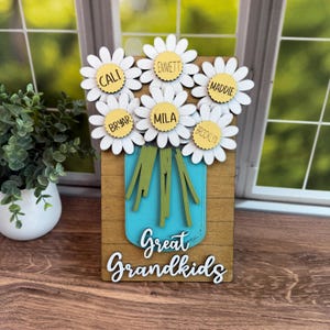May include: Wooden sign with a mason jar design and daisy flowers. Each daisy has a name: Cali, Emmett, Maddie, Bryar, Mila, and Brooklyn. The words "Great Grandkids" are written below the jar.