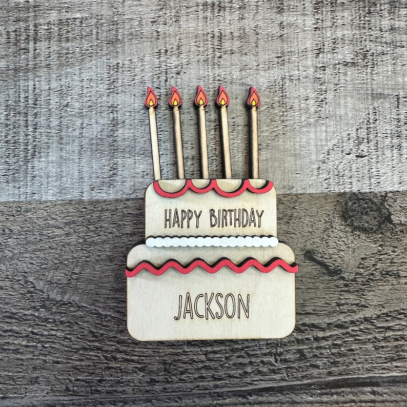 May include: Wooden birthday cake with five candles and the text "Happy Birthday Jackson".