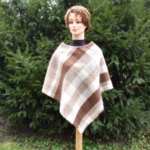 May include: A brown and white striped poncho with a diagonal pattern. The poncho is made of a soft, warm fabric and is perfect for layering in the fall or winter.