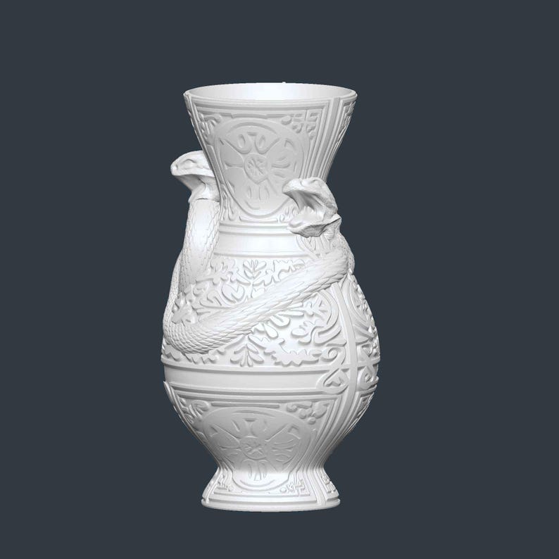 May include: White ceramic vase with a detailed relief design. Two snakes are wrapped around the vase, with their heads near the top. The vase has a wide base and a flared top, and is decorated with floral and geometric patterns.
