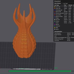 May include: An orange 3D-printed sculpture with a textured surface and a unique, organic shape. The design features multiple upward-reaching points and a bulbous base. The sculpture is displayed on a dark surface.