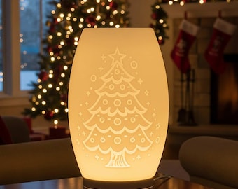 May include: A glowing, off-white Christmas tree-shaped lamp. The lamp features a detailed tree design with a star on top, illuminated against a festive background with a Christmas tree and fireplace. The lamp is on a table.