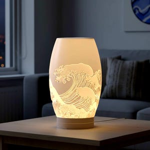 Puede incluir: Una lámpara de mesa color crema con un diseño de olas detallado tallado en la superficie. La lámpara, de forma ovalada, se apoya sobre una base redonda. La lámpara está encendida, iluminando el patrón de olas. La lámpara está sobre una mesa de madera.