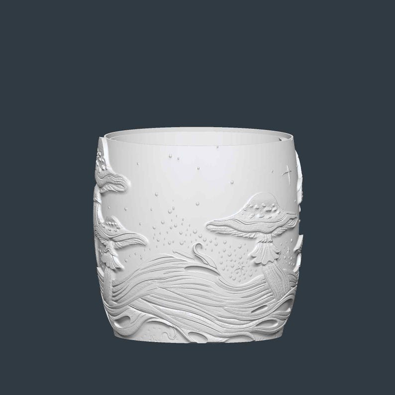 May include: A white, cylindrical drinking glass with an embossed design featuring mushrooms, flowing water, and stars. The design is raised, creating a textured surface. The glass has a smooth, rounded rim and a dark background.