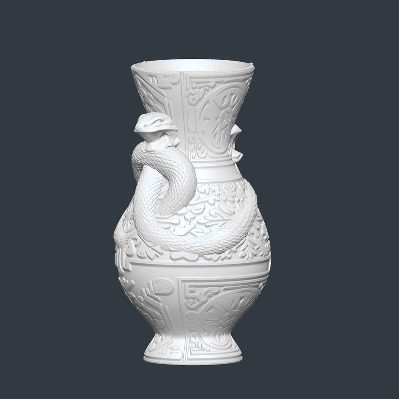 May include: White ceramic vase with intricate relief details and a coiled snake wrapped around the body. The vase features floral and geometric patterns, with a flared rim and a pedestal base. A decorative piece.
