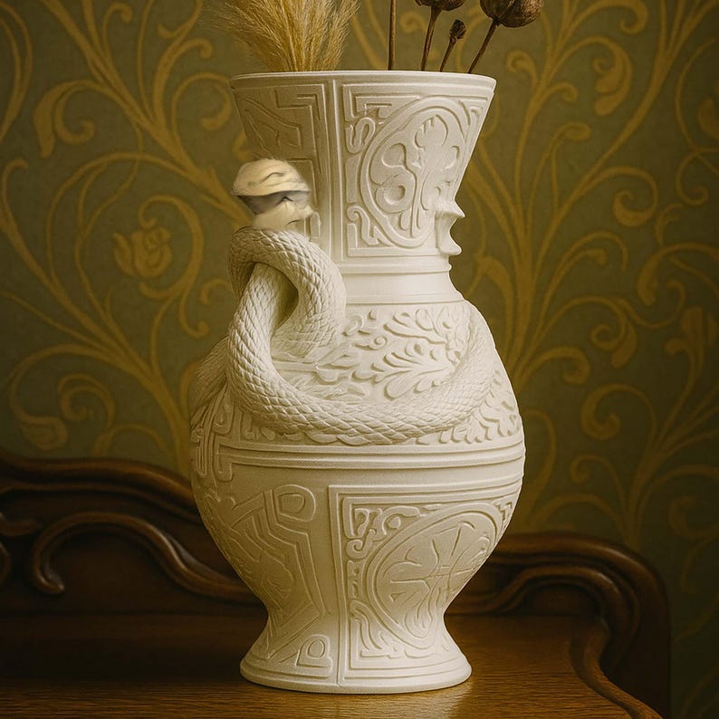 May include: A white ceramic vase with a detailed snake wrapped around the neck. The vase has an ornate design with carved patterns and is filled with dried plants. The vase is on a wooden surface.
