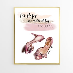 Op de afbeelding: Een printbare kunstprint met een aquarel achtergrond in roze en gouden tinten. De print toont een paar roze hoge hakken met een strik en de tekst "Haar stappen worden geordend door de HEERE. Psalm 37:23"