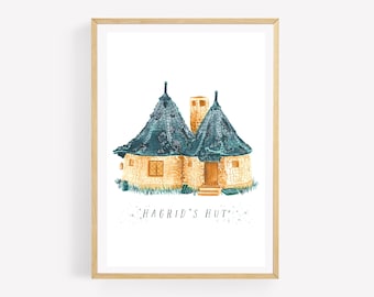 May include: Watercolor print of Hagrid's Hut, featuring a stone structure with a teal roof and chimney. The artwork is framed in a light wood frame. The text "Hagrid's Hut" is written below the image.