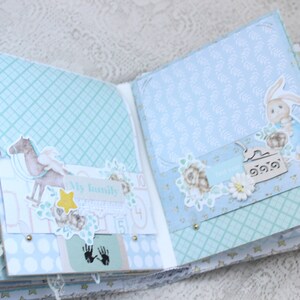May include: An open scrapbook with blue and white patterned pages. The pages are decorated with paper cutouts of a horse, a bunny, flowers, and a star. The text "My family" is visible on one of the pages.