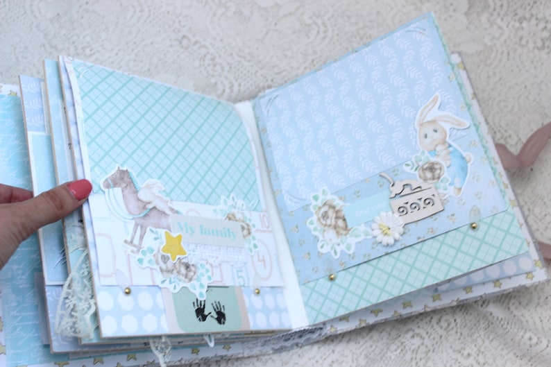 May include: An open scrapbook with blue and white patterned pages. The pages are decorated with paper cutouts of a horse, a bunny, flowers, and a star. The text "My family" is visible on one of the pages.