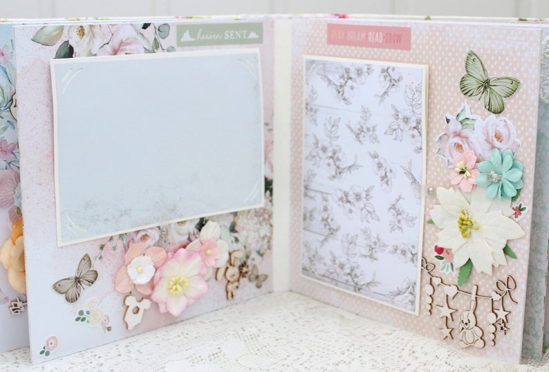 May include: A scrapbook page with a light blue background and floral embellishments. The page has a white frame with a light blue background and the text "Dream Read Relax" in a pink font. The page also has a white frame with a light blue background and the text "Forever Sent" in a pink font.