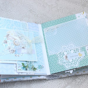 May include: A blue and white scrapbook with a bunny rabbit illustration, a white lace doily, and the text "bath time" on a yellow tag.
